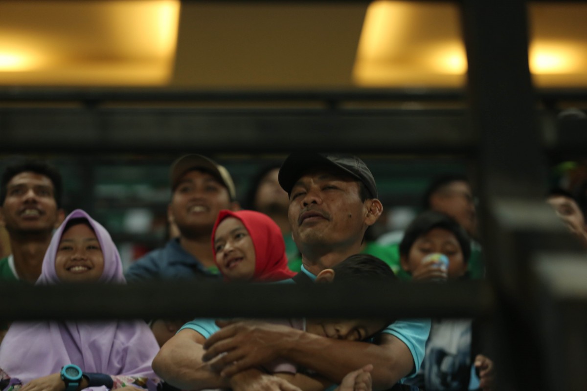 Salah satu Bonek sedang menyaksikan pertandingan bersama anaknya 